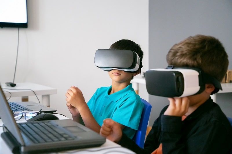 Little boys using VR headset and sitting at table